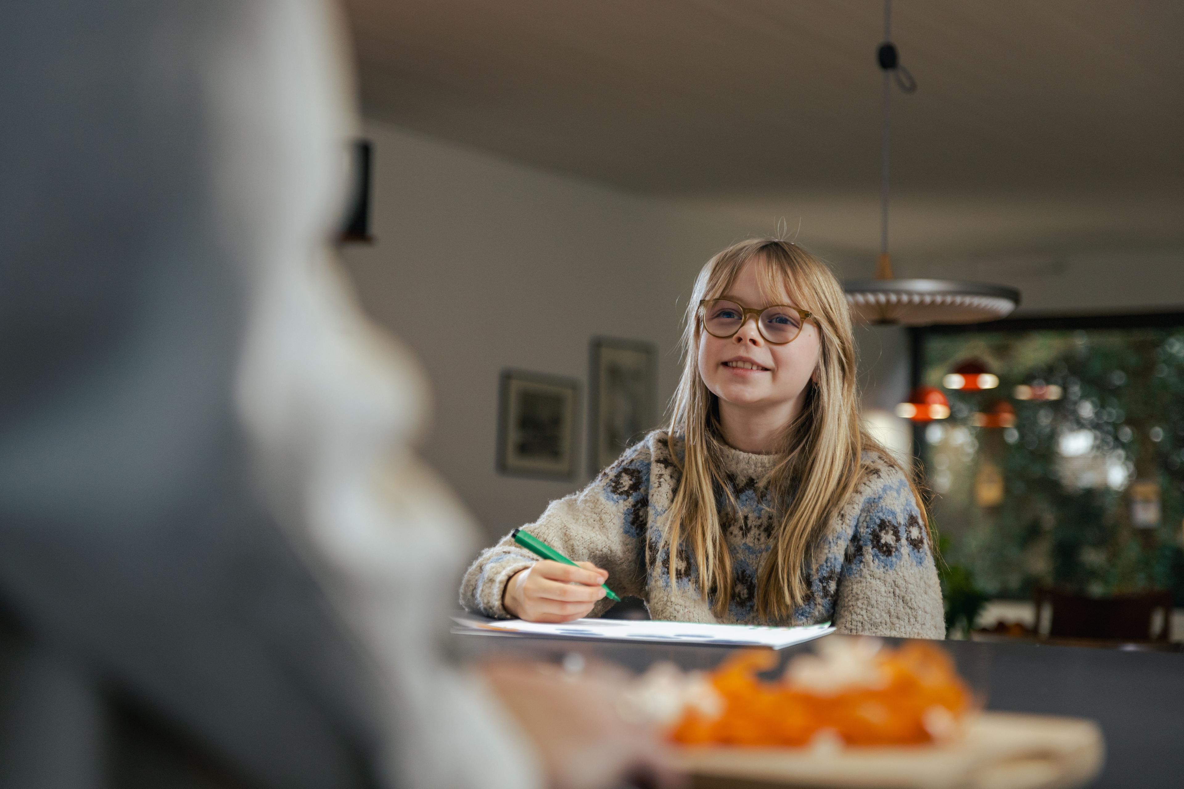 Pige laver lektier ved spisebordet