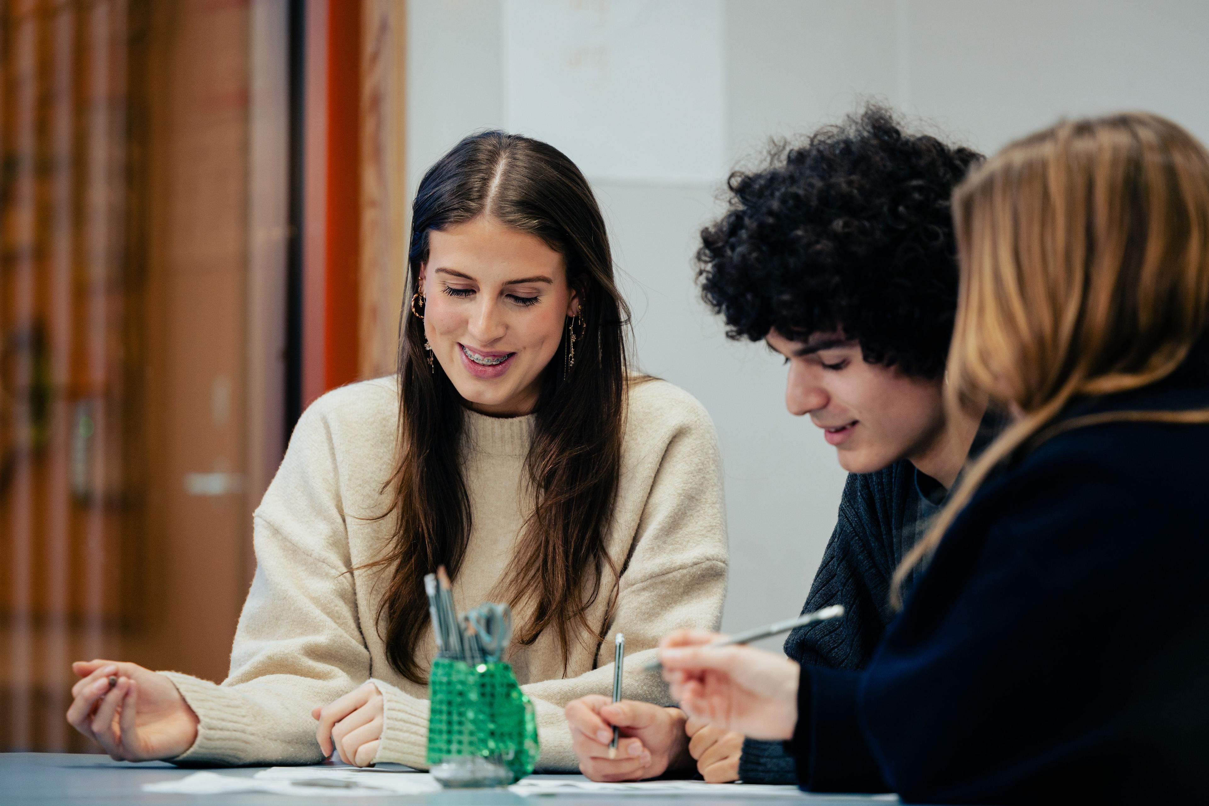 Tre unge sidder i klasseværelset og arbejder med en gruppeøvelse