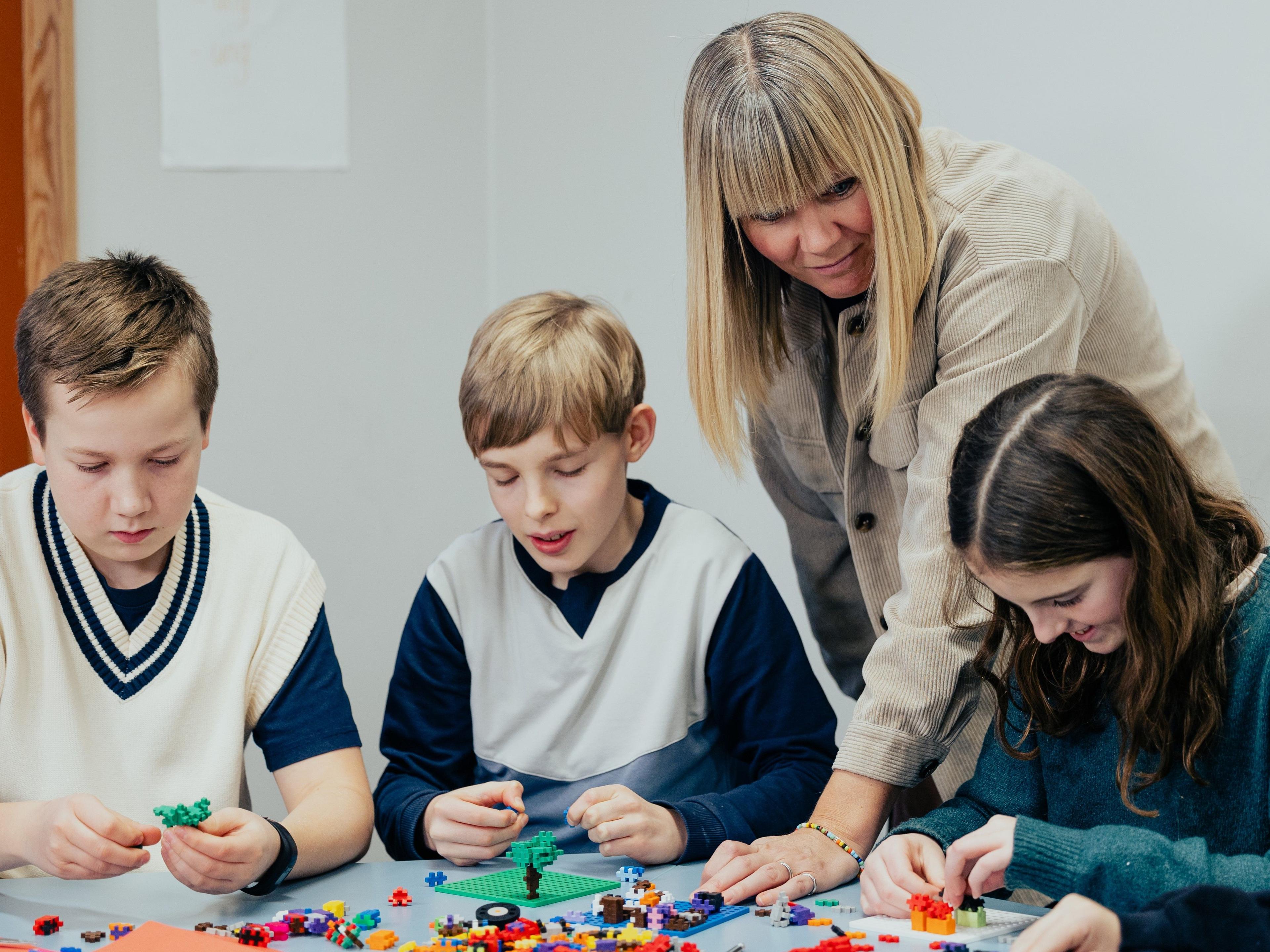 Skolelærer med elever der bygger Lego