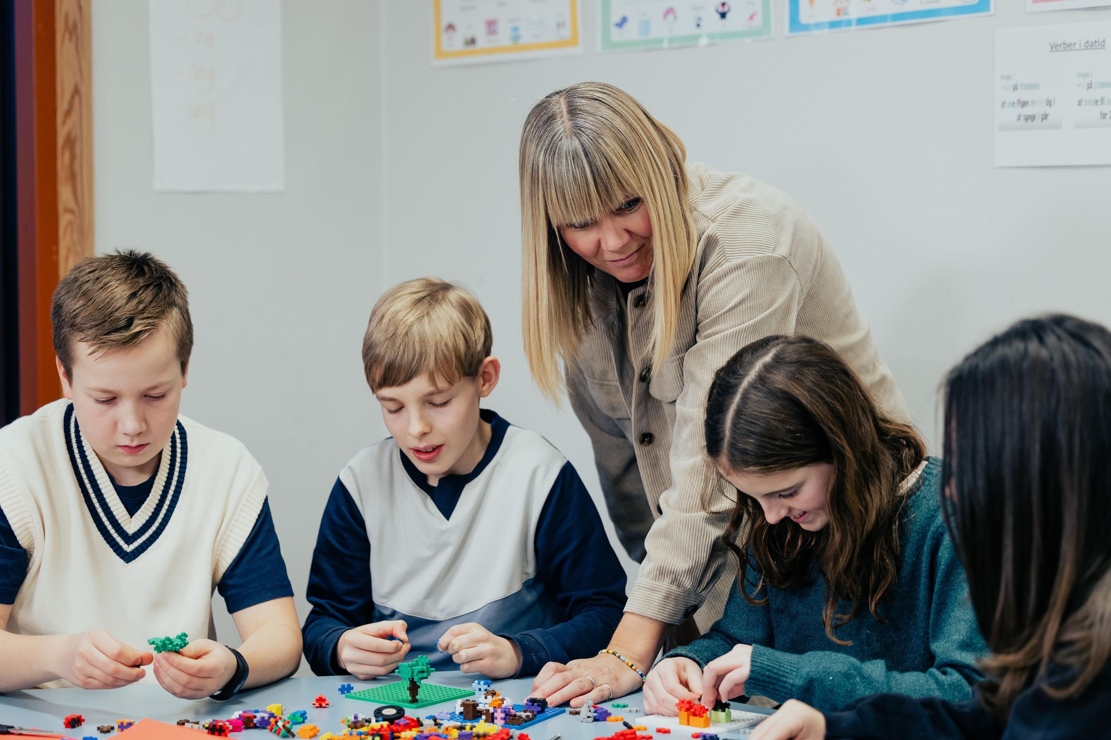 Fire elever arbejder plus-plusser imens deres lærer deltager